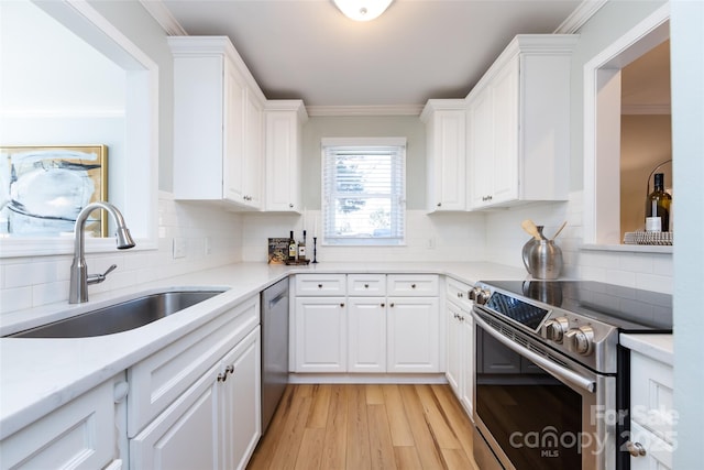 kitchen featuring appliances with stainless steel finishes, white cabinetry, a sink, and ornamental molding