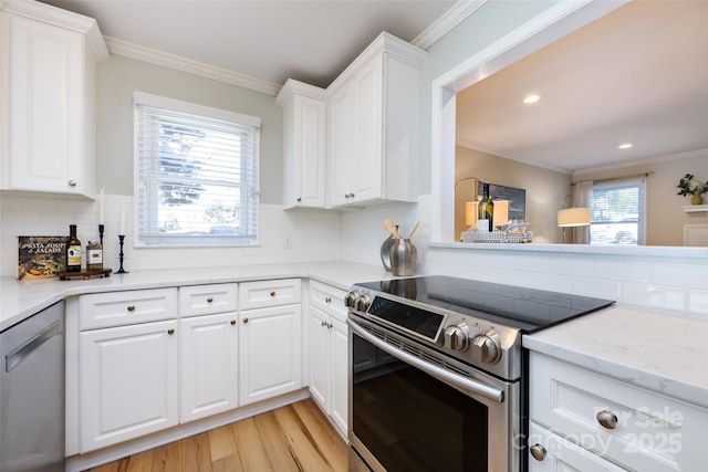 kitchen with ornamental molding, appliances with stainless steel finishes, and white cabinetry