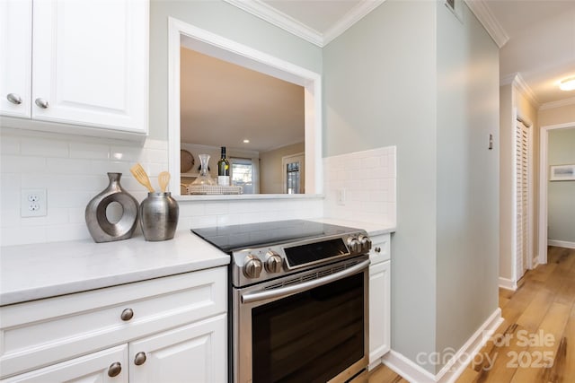 kitchen featuring white cabinets, electric stove, ornamental molding, light countertops, and light wood-type flooring