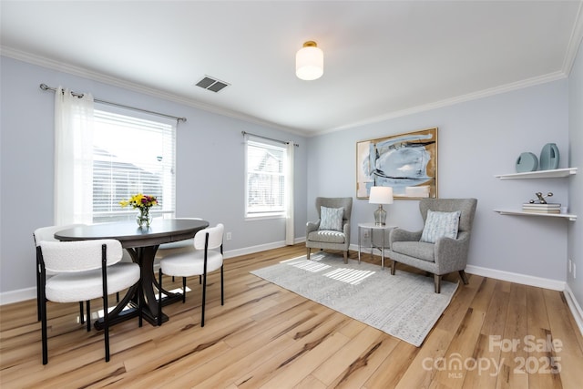 living area with baseboards, wood finished floors, visible vents, and crown molding