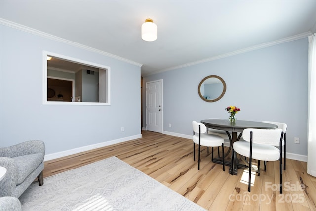 dining room with crown molding, wood finished floors, visible vents, and baseboards