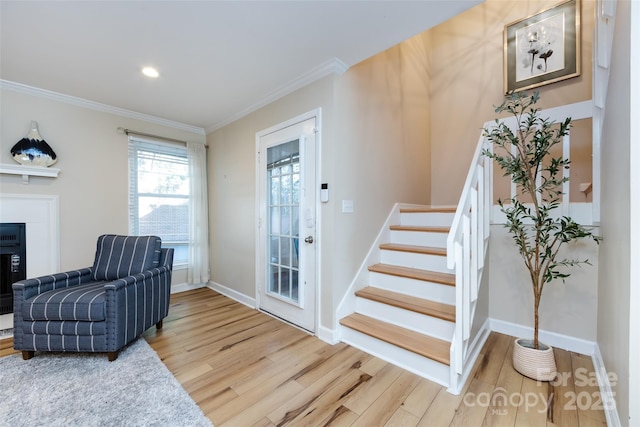 entryway with ornamental molding, light wood-type flooring, and stairs