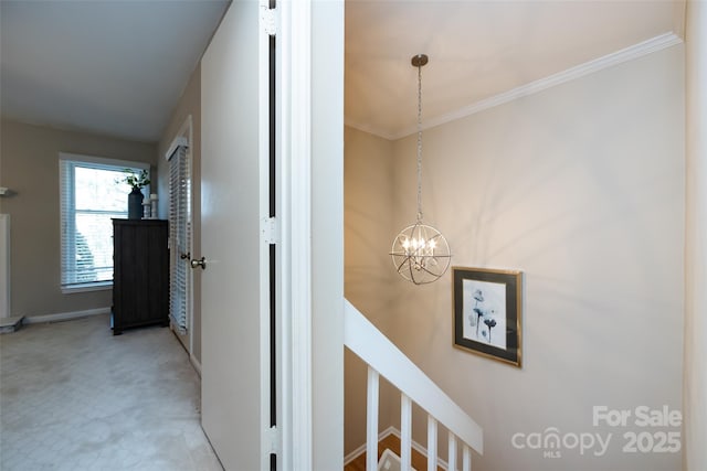 hall with baseboards, ornamental molding, an upstairs landing, carpet floors, and a chandelier