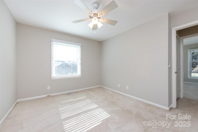 empty room with light carpet, baseboards, visible vents, and a ceiling fan