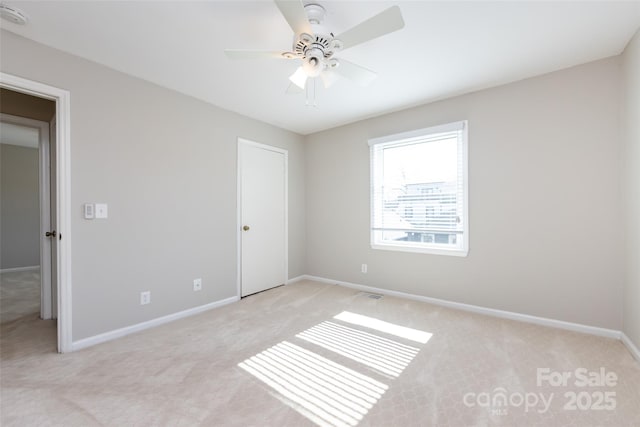 spare room with light carpet, ceiling fan, and baseboards