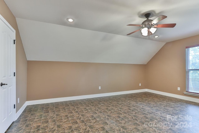 additional living space featuring ceiling fan, dark tile patterned flooring, and lofted ceiling