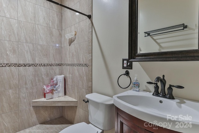 bathroom with vanity, toilet, and tiled shower