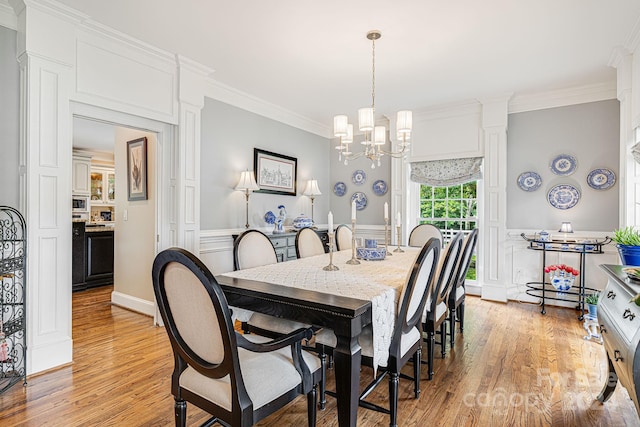 dining space with crown molding, light hardwood / wood-style flooring, and a chandelier