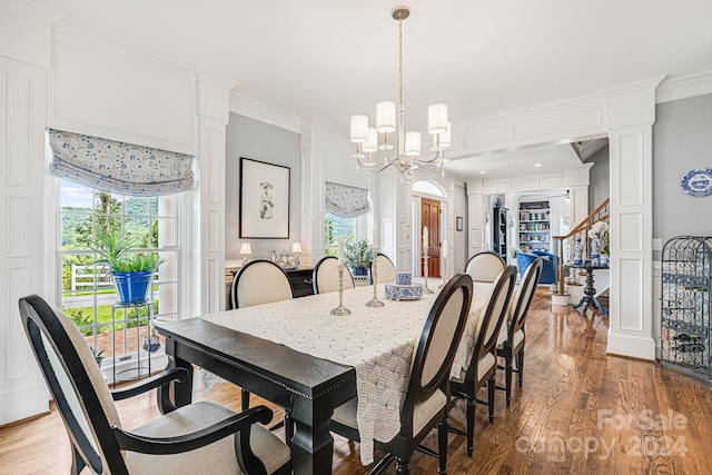 dining area with light wood-type flooring, ornamental molding, and an inviting chandelier