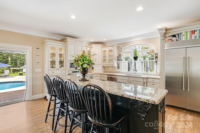 kitchen featuring appliances with stainless steel finishes, light hardwood / wood-style flooring, light stone countertops, and a healthy amount of sunlight