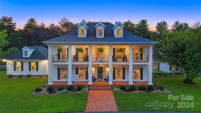 view of front facade featuring covered porch, a balcony, and a lawn