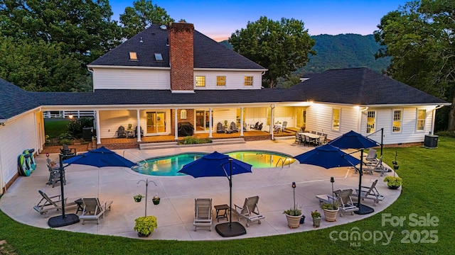 56 Fair Oaks Est, Fletcher, NC 28732 - back of property at dusk featuring a lawn, a chimney, an outdoor pool, a patio, and roof with shingles