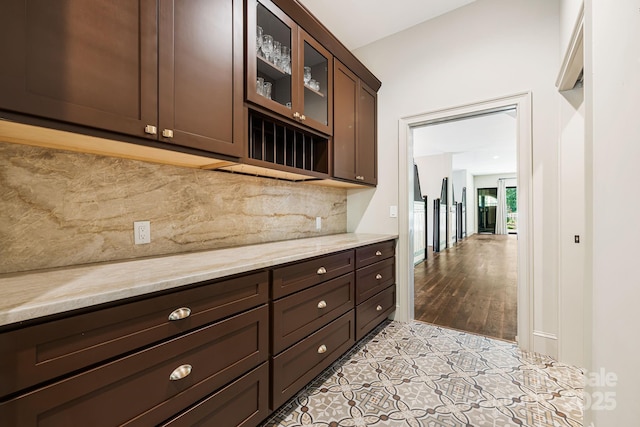 56 Fair Oaks Est, Fletcher, NC 28732 - kitchen with dark brown cabinets, backsplash, glass insert cabinets, light stone counters, and light tile patterned floors