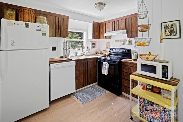 kitchen with light wood-type flooring, white appliances, and sink