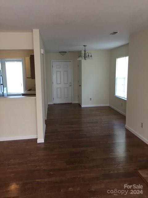 unfurnished living room with dark hardwood / wood-style floors and a notable chandelier