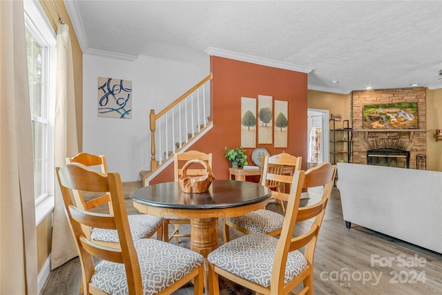 dining room featuring light wood-type flooring, a fireplace, and a textured ceiling