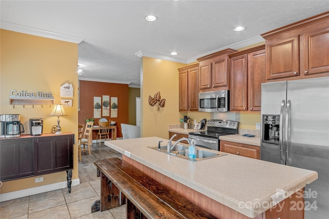 kitchen featuring light tile patterned flooring, appliances with stainless steel finishes, an island with sink, ornamental molding, and sink