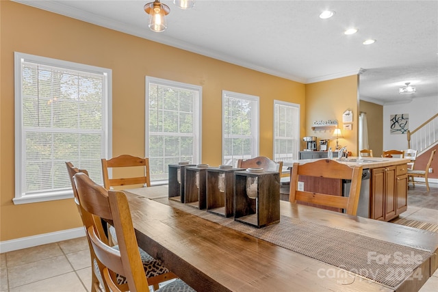 dining space featuring sink, ornamental molding, light tile patterned floors, and a healthy amount of sunlight