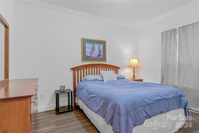 bedroom with ornamental molding and hardwood / wood-style floors