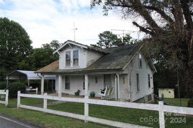 view of front of house featuring a carport, covered porch, and a front yard