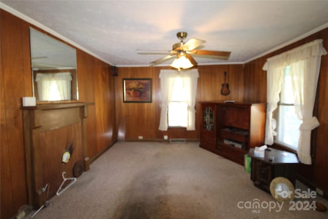 interior space featuring wood walls, ceiling fan, a wealth of natural light, and crown molding