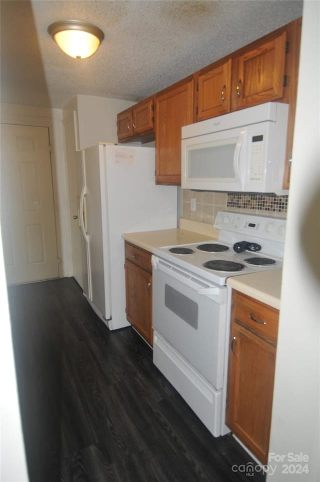 kitchen featuring dark hardwood / wood-style floors, decorative backsplash, white appliances, and a textured ceiling