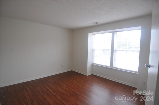 empty room featuring a textured ceiling and hardwood / wood-style flooring