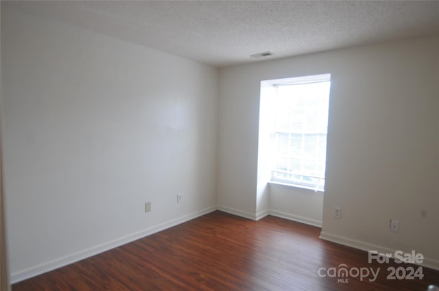 empty room featuring a textured ceiling and wood-type flooring