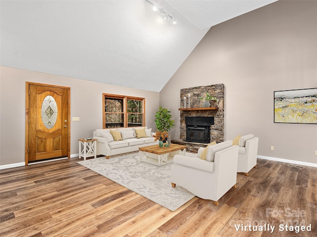 living room featuring a fireplace, hardwood / wood-style floors, rail lighting, and high vaulted ceiling