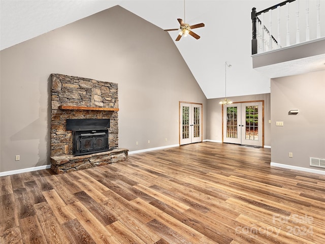 unfurnished living room featuring wood-type flooring, ceiling fan, high vaulted ceiling, french doors, and a stone fireplace