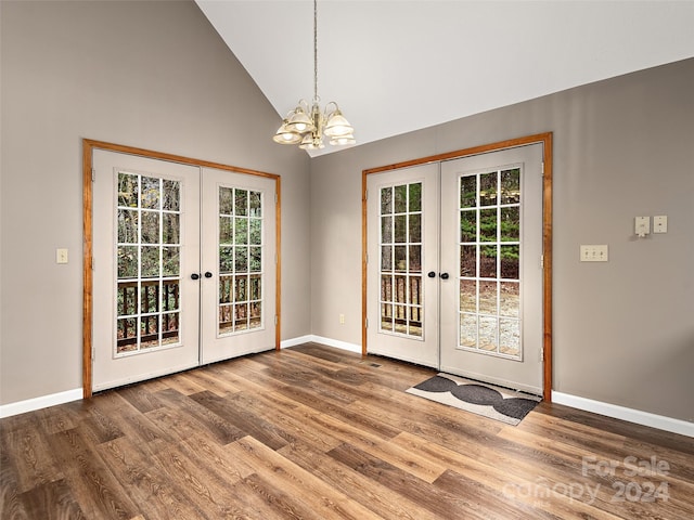 doorway to outside with hardwood / wood-style flooring, an inviting chandelier, french doors, and high vaulted ceiling