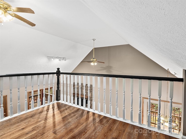 corridor with hardwood / wood-style flooring, vaulted ceiling, and a textured ceiling