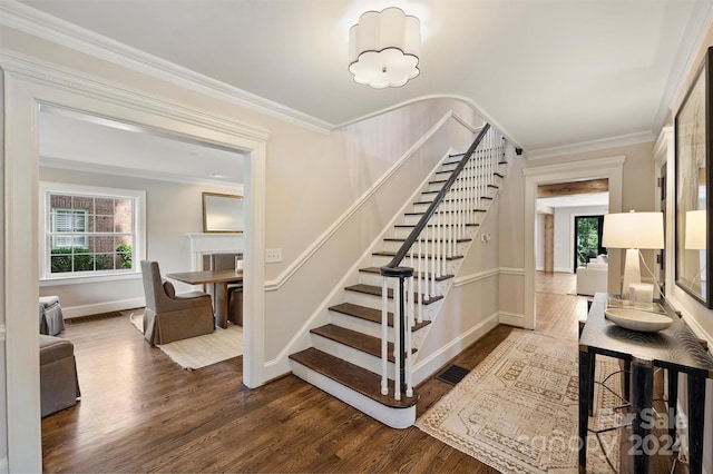 stairway featuring wood-type flooring, a fireplace, and ornamental molding