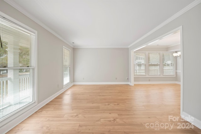 spare room featuring a notable chandelier, ornamental molding, and light hardwood / wood-style flooring