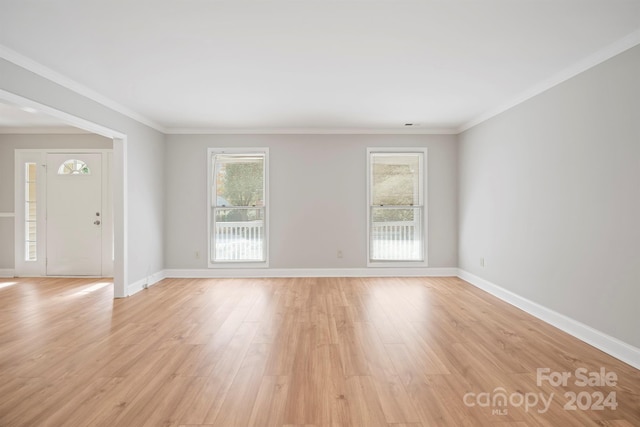 empty room with ornamental molding and light hardwood / wood-style flooring