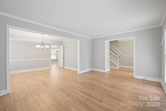 spare room featuring a notable chandelier, crown molding, and light hardwood / wood-style flooring