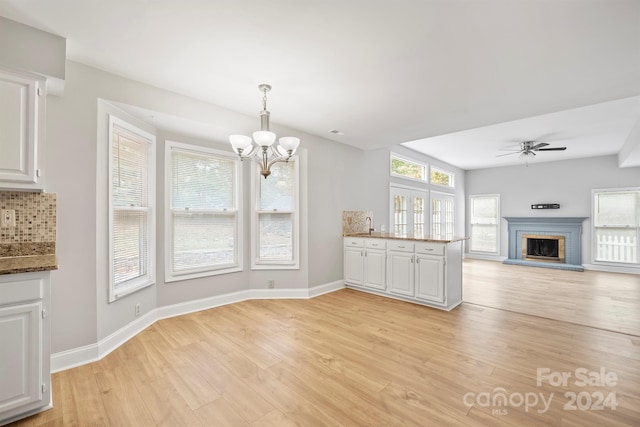 kitchen with white cabinetry, pendant lighting, decorative backsplash, and light hardwood / wood-style flooring