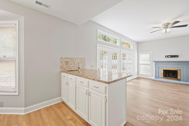 kitchen featuring white cabinets, a wealth of natural light, light stone countertops, and light hardwood / wood-style floors