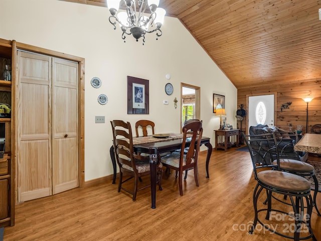 dining space with vaulted ceiling, light hardwood / wood-style floors, wooden ceiling, and an inviting chandelier