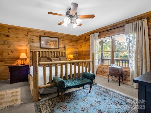 carpeted bedroom featuring ceiling fan and wooden walls