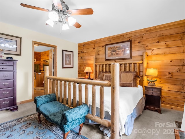 carpeted bedroom featuring ceiling fan and wood walls