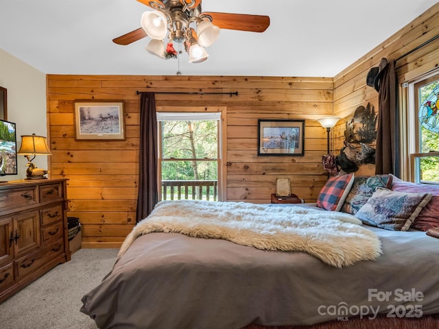 bedroom with ceiling fan, wood walls, and light carpet