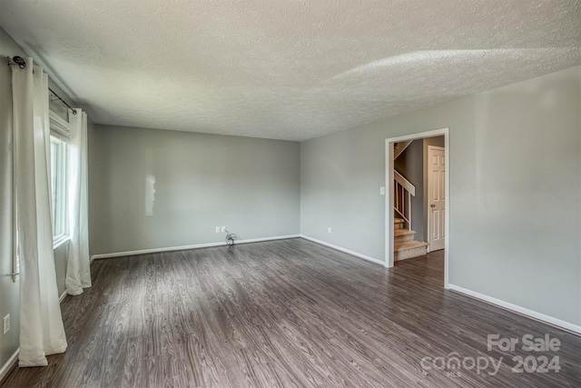 spare room with a textured ceiling and dark hardwood / wood-style flooring