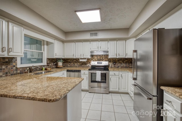 kitchen with decorative backsplash, appliances with stainless steel finishes, kitchen peninsula, light tile patterned flooring, and sink