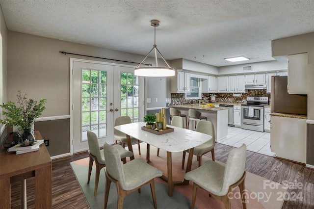 dining area with french doors, light hardwood / wood-style flooring, and a textured ceiling