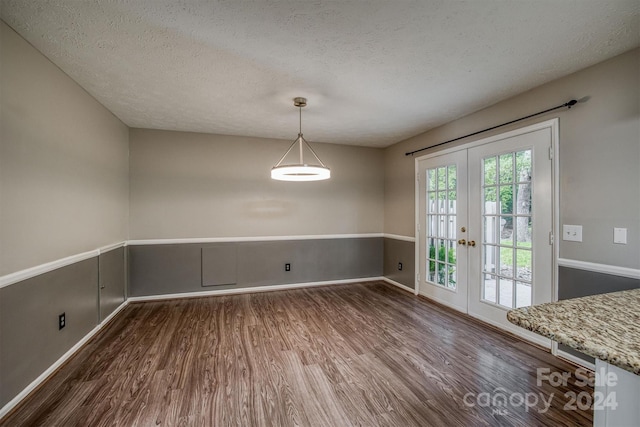 unfurnished dining area with french doors, dark hardwood / wood-style flooring, and a textured ceiling