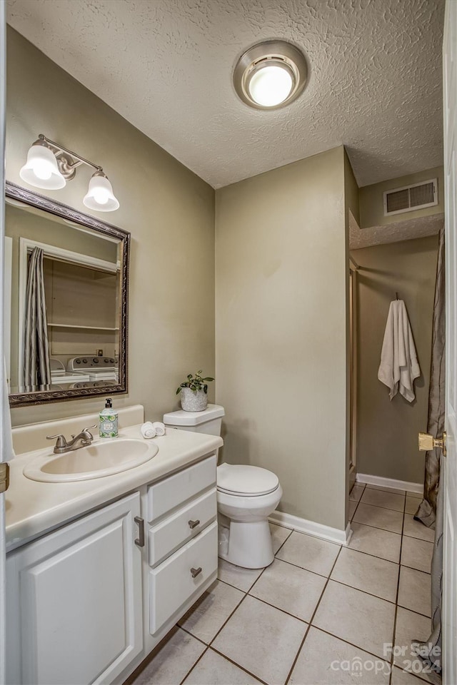 bathroom featuring vanity, a textured ceiling, toilet, and tile patterned flooring