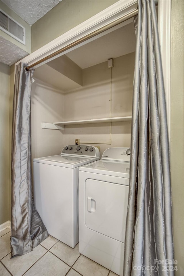 clothes washing area with independent washer and dryer and light tile patterned floors