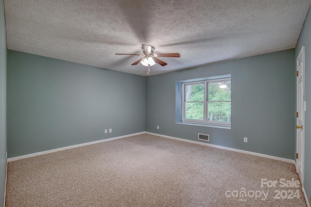 empty room featuring a textured ceiling, carpet, and ceiling fan