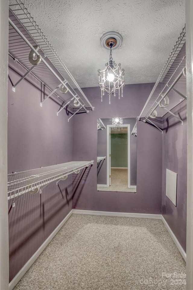 spacious closet with a notable chandelier and carpet